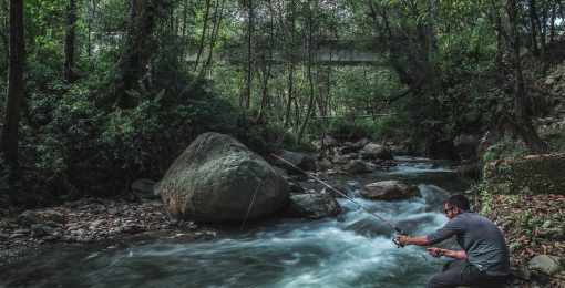 Un homme pêche dans la rivière d'une forêt en France